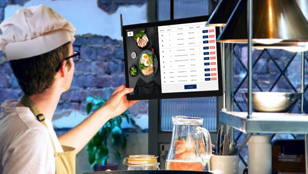 Chef using a tablet to manage kitchen orders in a restaurant setting.