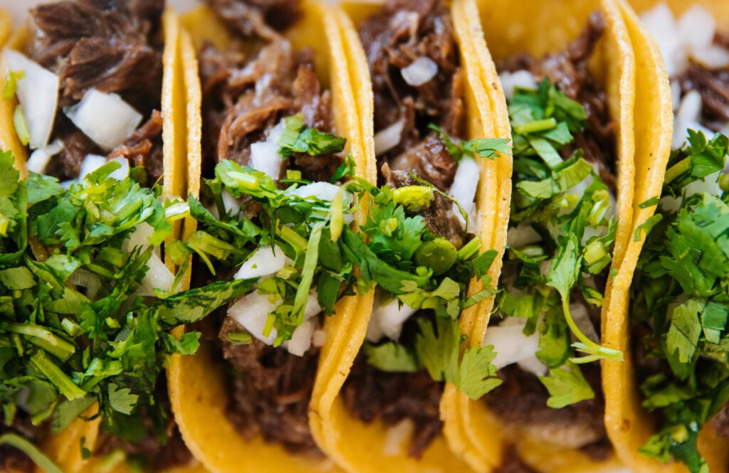 Close-up of delicious beef tacos topped with fresh cilantro and onions, perfect for Mexican cuisine lovers.