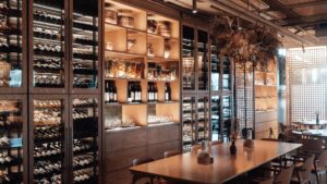 Wall with shelves with collection of assorted wine in modern restaurant with wooden furniture and creative decor